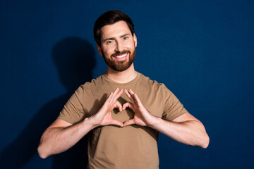 Sticker - Photo of grateful man with stylish beard haircut dressed beige t-shirt showing heart on chest isolated on dark blue color background