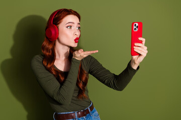 Wall Mural - Photo of girlish lovely lady dressed shirt earphones sending kiss modern gadget empty space isolated green color background