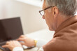 © Prostock-studio - Unrecognizable Elderly Man Using Laptop Looking At Blank Screen Sitting Indoor. Computer Literacy For Senior People