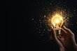 © PrusarooYakk - Hands holding a glowing light bulb with sparkling particles in the dark, symbolizing creativity, innovation, and bright ideas.