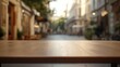 © BerkahStock - A wooden table in focus, set against a blurred street scene in an urban environment.