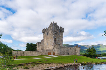 a castle with a large tower sits on a hill overlooking a lake