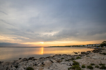 Wall Mural - Beach in the morning. Sunrise, pebble beach on a rocky coast. The sky is reflected in the water of a bay. Natural spectacle of a Mediterranean landscape, island of Vir, Zadar, Dalmatia, Croatia, Adria