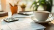 © BROPRADANA - Close up of a cup of tea and a calculator on a desk with paperwork.