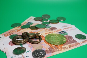 Canvas Print - A metal snake figurine and bitcoin on a green background. Business and finance.