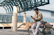 © Dorde - Businessman Engaging with Smartphone Beside Bicycle Outdoors