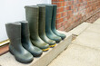 © Tosh - 3 pairs mid and full height green rubber outdoor gardening wellington boots lined up in row on doorstep