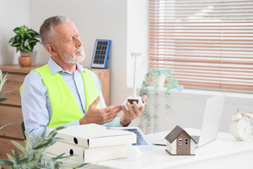 Sticker - Mature engineer with wind turbine model at table in office