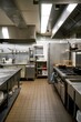 © BISO - An empty restaurant kitchen with various professional cooking equipment. There's a large stainless steel oven, a six-burner stove with cast iron pots, a refrigerator and a dishwasher.