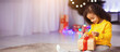 © Prostock-studio - Cozy Christmas evening. Cute african kid opening Xmas gift at home, free space