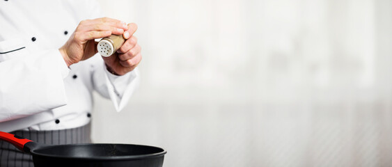 Unrecognizable Chef Adding Pepper Seasoning Disn In Frying Pan Cooking In Kitchen Indoor. Cropped, Empty Space, Selective Focus