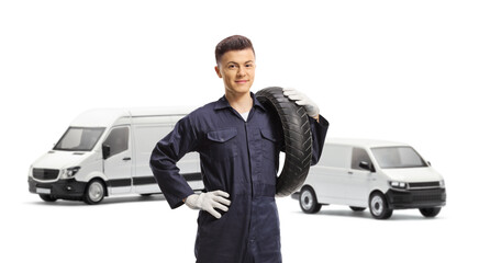 Canvas Print - Mechanic worket with vans carrying a tire and smiling at camera