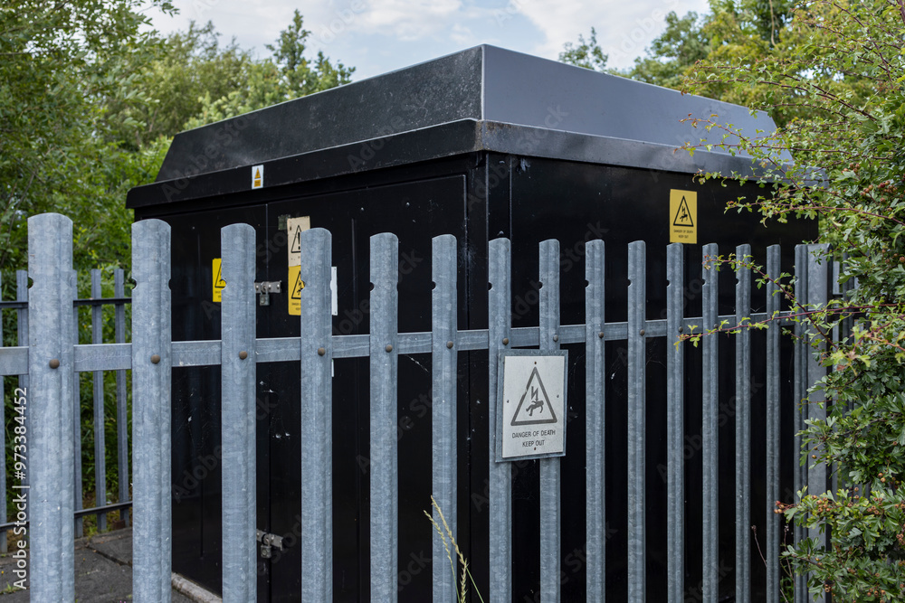 Black suburban electricity substation with galvanized metal fence ...