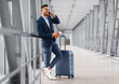 © Prostock-studio - Mobile Call. Smiling Young Middle Eastern Businessman Talking On Cellphone In Airport While Waiting With Suitcase For Flight At Terminal, Happy Arab Man Having Pleasant Phone Conversation