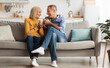 © Prostock-studio - Happy Senior Couple Drinking Coffee Holding Mugs With Hot Drink And Smiling To Each Other Sitting On Couch At Home. On Weekend. Retirement Lifestyle And Happy Marriage Concept