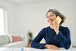 © insta_photos - Happy middle aged woman making phone call sitting at table in living room. Smiling mature older lady having mobile conversation talking on the phone while relaxing at home. Copy space for ads.