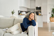 © insta_photos - Happy relaxed 50 years old woman laying on sofa at home looking away. Smiling middle aged lady posing in living room at home. Mature older female with curly gray hair relaxing on couch enjoying chill