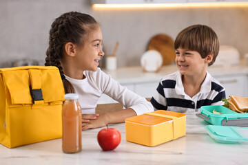 Wall Mural - Cute children preparing school lunch boxes with healthy food at white marble table in kitchen