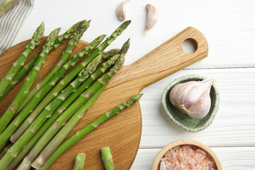 Wall Mural - Fresh green asparagus stems, garlic and sea salt on white wooden table, flat lay