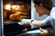 © Prostock-studio - Housewife preparing roasted chicken in oven at kitchen, free space