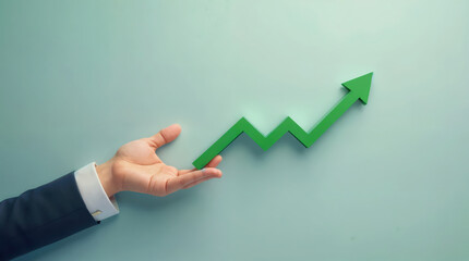 Business professional's hand gesturing towards upward trending green arrow graph, symbolizing growth, success, and positive financial performance