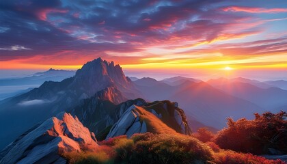 Majestic mountain peak at sunset with vibrant hues and mist-covered valleys creating a breathtaking landscape