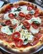 © sirisakboakaew - Juicy pizza with a crispy crust, loaded with fresh tomatoes, mozzarella, and basil