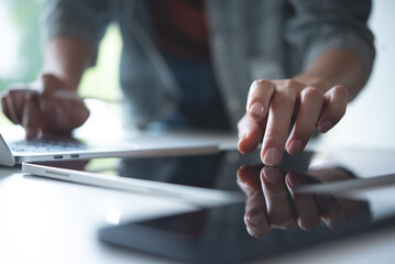 Poster - Close up, woman using digital tablet and working on laptop computer on office table. Graphic designer using mobile app on tablet, finger touching on screen