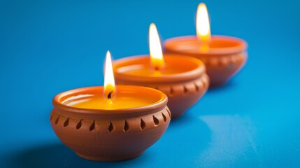 Three lit candles in clay bowls on a blue background