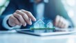 © praewpailyn - A person interacts with a digital display of houses, showcasing modern technology in real estate and property management.