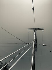 Sepia-toned image of a utility pole with crisscrossing wires against a hazy sky in Carlsbad, CA.