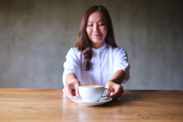 Canvas Print - Portrait image of a woman holding and serving a cup of hot coffee