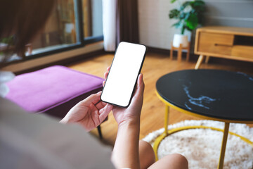 Wall Mural - mockup image of a woman holding mobile phone with blank desktop white screen at home