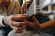 © DragonImages - Close-up of hands fretting on guitar strings while another person guides playing technique. No visible faces enhancing learning experience and focusing on guitar frets