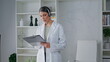 © stockbusters - Doctor headset reading information clipboard in medicare clinic. Woman therapist