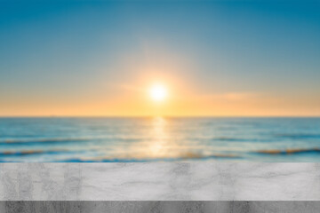 Empty white marble table at sunset with blur beach sea bokeh background with green leaf foreground, Mock up template for display or montage of product or content use as banner in social media ads