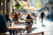 © Ilia - Blurred background of People sitting at tables in outdoor cafe, on bustling street. Relaxed atmosphere, featuring individuals enjoying coffee and casual conversation in lively city environment.