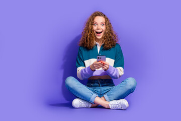 Wall Mural - Full size photo of nice young girl sit floor hold smart phone isolated on violet color background