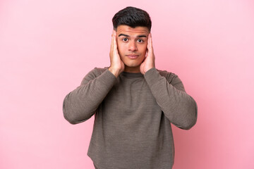 Young caucasian handsome man isolated on pink background frustrated and covering ears