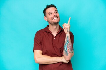 Wall Mural - Young caucasian handsome man isolated on blue background pointing up a great idea