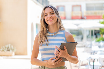 Sticker - Young pretty woman holding a tablet at outdoors smiling a lot