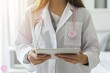 © lenblr - Doctor wearing a pink ribbon stethoscope using a digital tablet in a hospital room