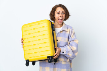 Young English woman isolated on white background in vacation with travel suitcase and surprised