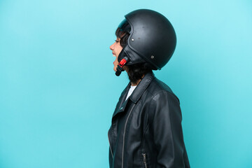 Sticker - Young Argentinian woman with a motorcycle helmet isolated on blue background laughing in lateral position