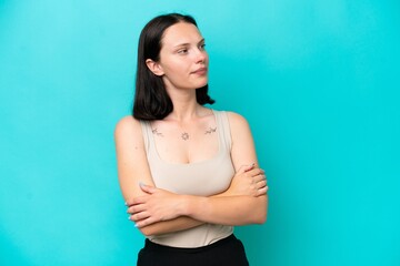 Young caucasian woman isolated on blue background looking to the side