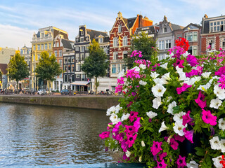 Amsterdam downtown cityscape, canal bridge, decorated with flowers, old houses on background, at sunset in summer. Travel to famous city of Europe Amsterdam, Holland, Netherlands