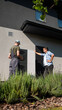 © StockMediaSeller - A technician and a homeowner inspecting a heat pump unit outside a house in the garden.