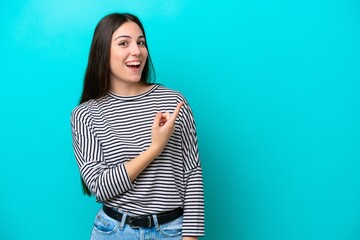 Wall Mural - Young caucasian woman isolated on blue background surprised and pointing side