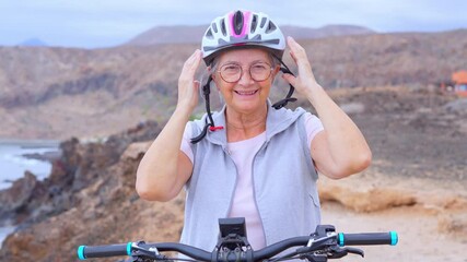 Canvas Print - Portrait of one old woman smiling and enjoying nature outdoors riding bike with her husband laughing. Headshot of mature female with glasses feeling healthy. Senior putting on helmet to go trip 