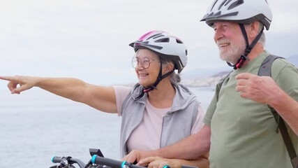 Canvas Print - Two happy old mature people enjoying and riding bikes together to be fit and healthy outdoors. Active seniors having fun training in nature. Portrait of one old man smiling in a bike trip with 